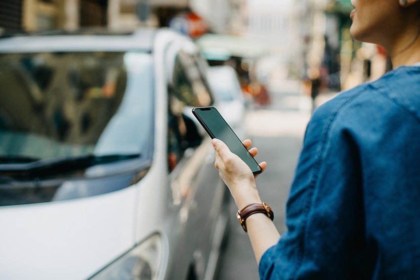 Frau am Telefon, die in Richtung eines Autos schaut
