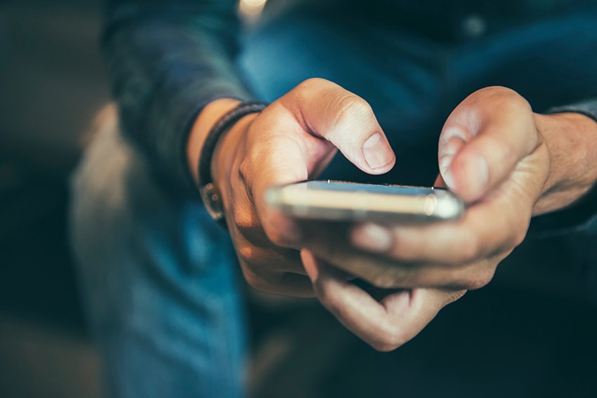 Person, die auf einem Mobiltelefon Textnachrichten schreibt